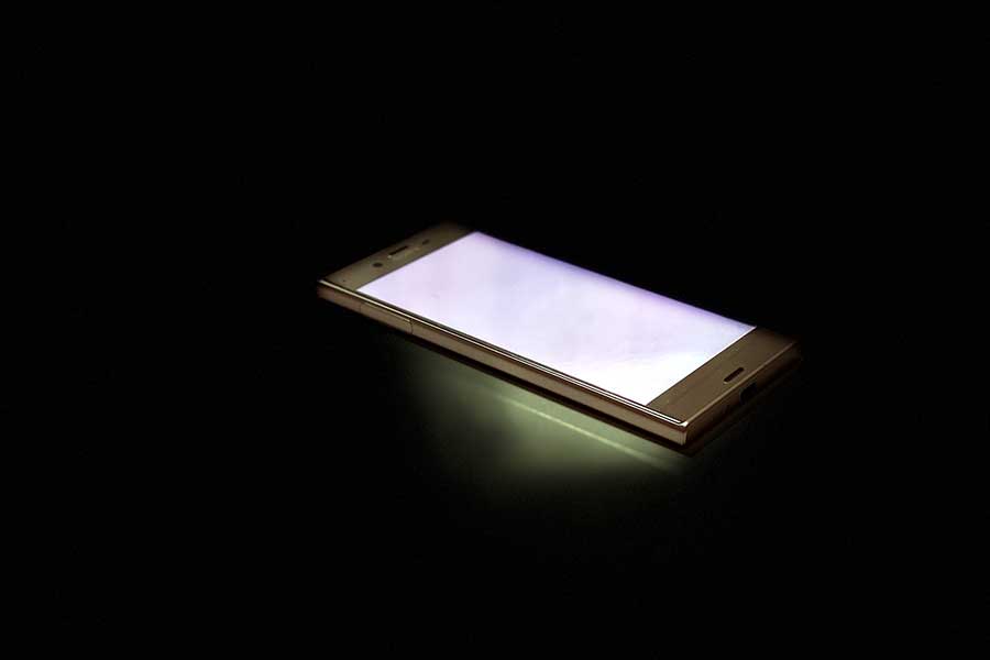 暗闇の中で光るスマートフォン（写真はイメージ）【写真：写真AC】
