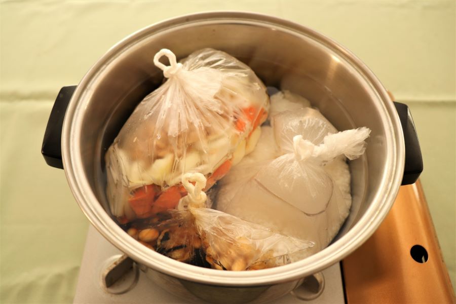 アイラップで炊飯やおかずの温めが同時にできる。鍋肌に袋が触らないように注意（写真はイメージ）【写真：写真AC】