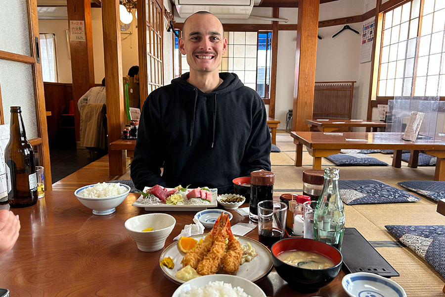 座敷席で刺身やエビフライなどの日本食を堪能するベンジャミンさん【写真提供：エル】