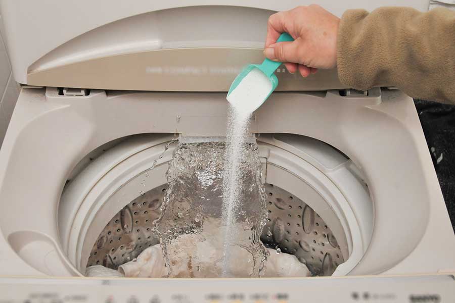 洗濯機に衣類用洗剤を投入（写真はイメージ）【写真：写真AC】