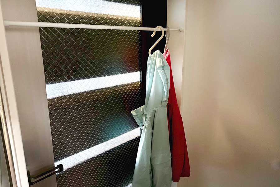 ドア枠を上手に使って、突っ張り棒を頭よりも上の位置に設置。隅で干せば出入りの邪魔にならない【写真：伊藤まき】