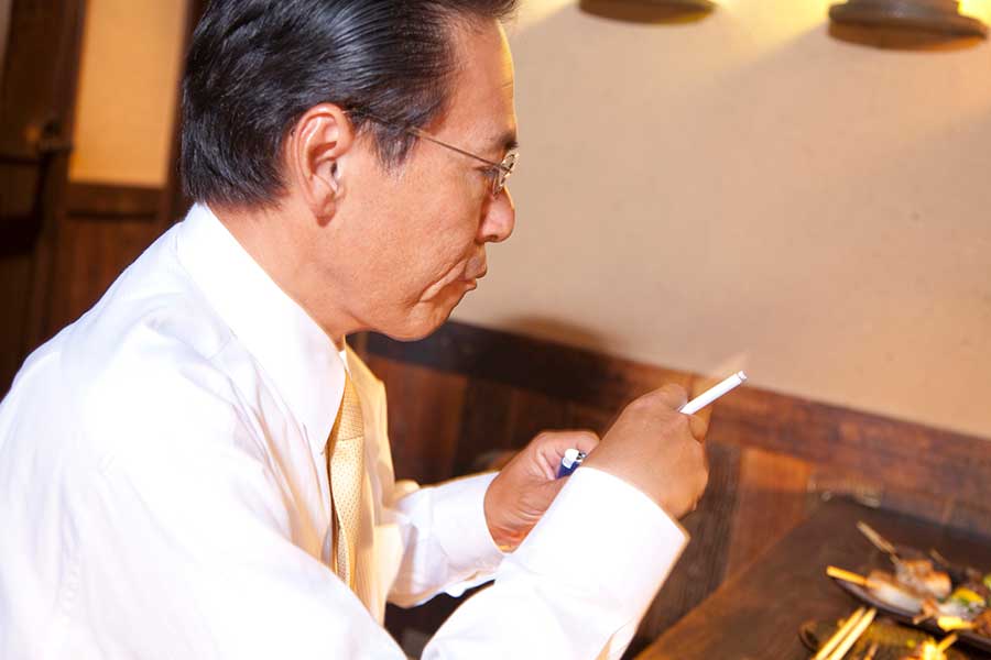 居酒屋でタバコを吸う男性（写真はイメージ）【写真：PIXTA】
