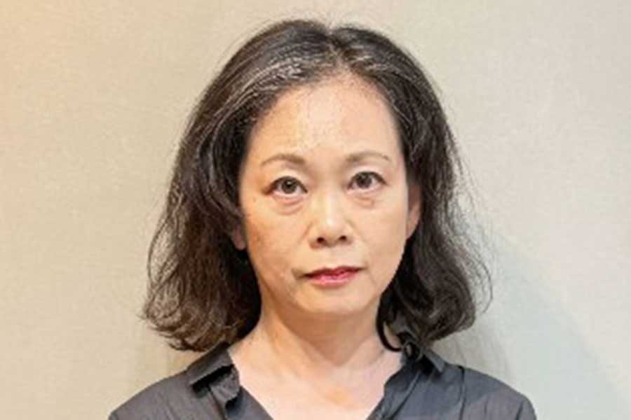 癖毛でうねった、白髪混じりの髪が目立つ女性(スクリーンショット)