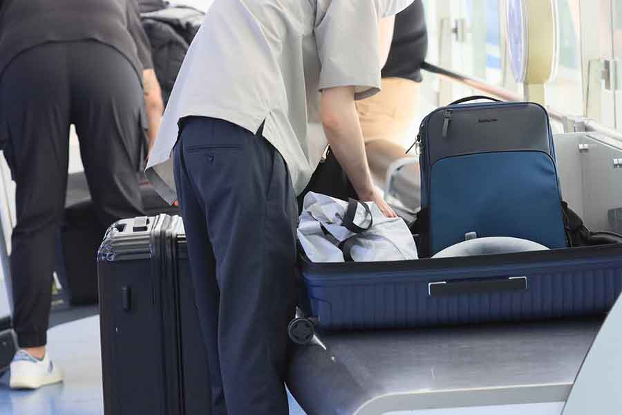 空港の出発ロビーでスーツケースの荷物を詰め替える外国人観光客（写真はイメージ）【写真：PIXTA】
