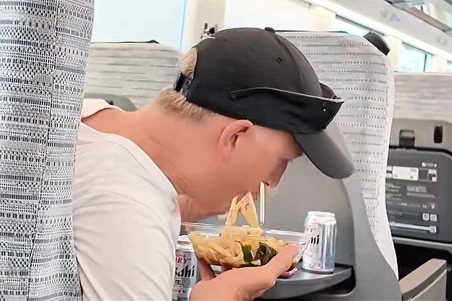 冷やしうどんに天かすなどのトッピングを入れて、食べ始めたチャールズさん（スクリーンショット）