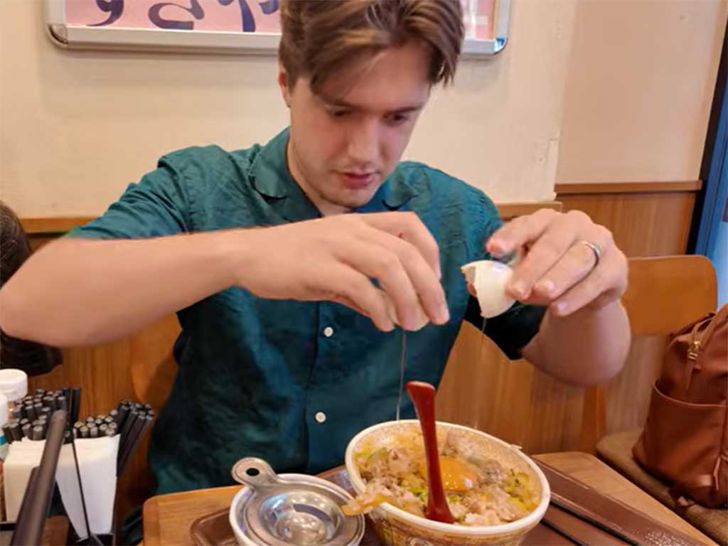 生卵をのせた牛丼に挑戦したスペンサーさん（スクリーンショット）