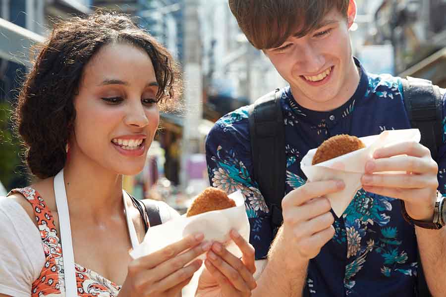 食べ歩きをする外国人観光客（写真はイメージ）【写真：PIXTA】