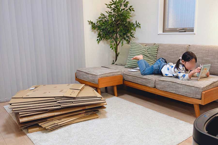 制作前、リビングに積み重ねられた大量の段ボール。ソファでは娘さんがくつろいでいる【写真提供:黒主くん(@kuronushi_)さん】
