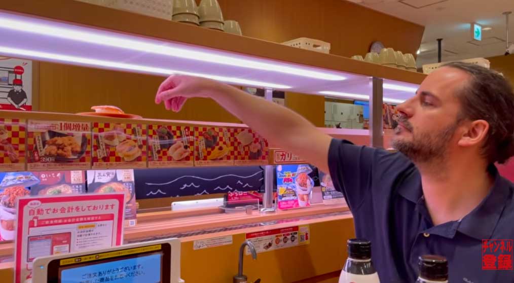 注文した寿司がテーブル横でぴたりと止まり、手に取るベンさん【出典：YouTube「Trilingual Family ドイツ在住4人家族」よりスクリーンショット】