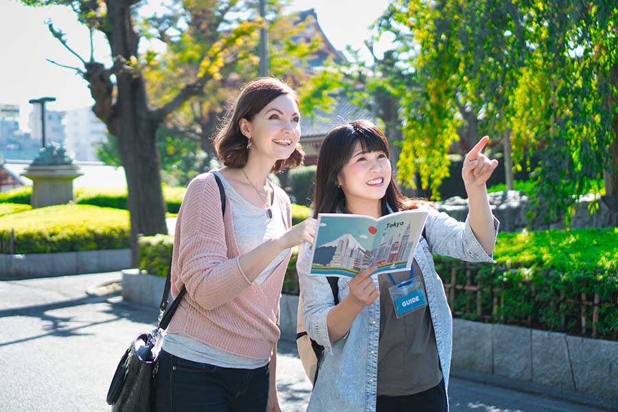 外国人に笑顔で道を教えている日本人（写真はイメージ）【写真：PIXTA】