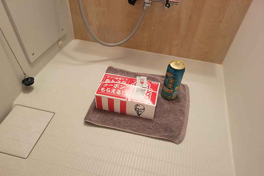 浴室にぽつんと置かれた、チキンが入った箱と缶ビール【写真提供：しぴこめ（@chipie0826）さん】