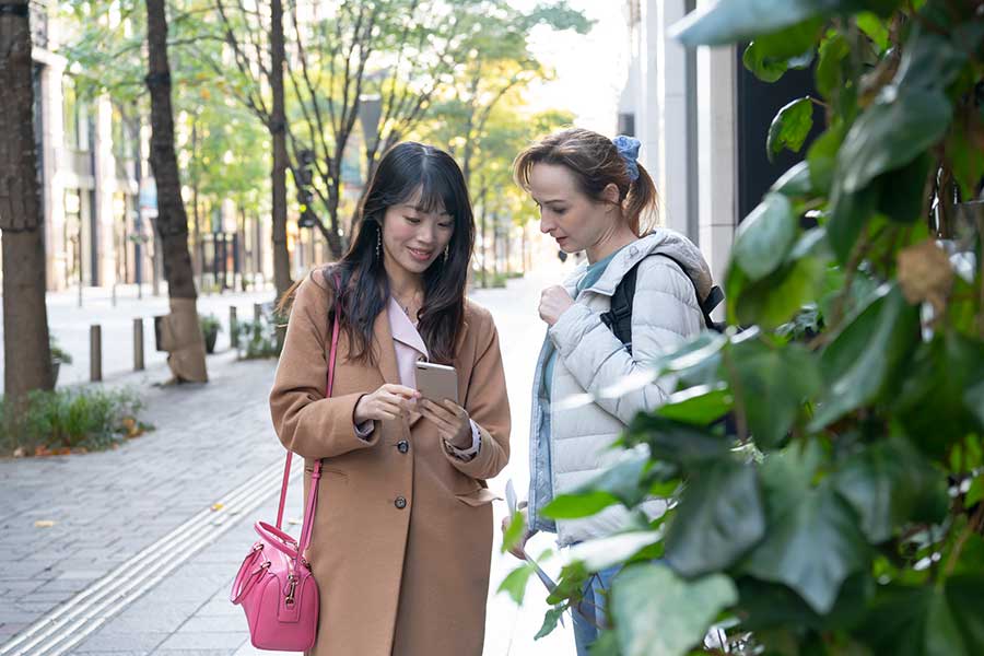 スマホを使って外国人に道案内をする日本人（写真はイメージ）【写真：PIXTA】