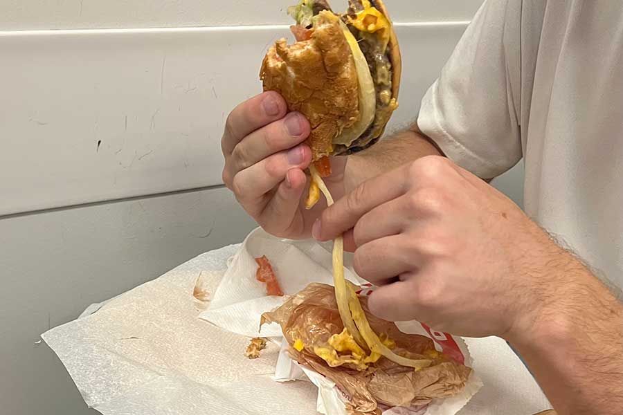 玉ねぎをこぼしながらハンバーガーを食べるスイス人【写真：Yo】