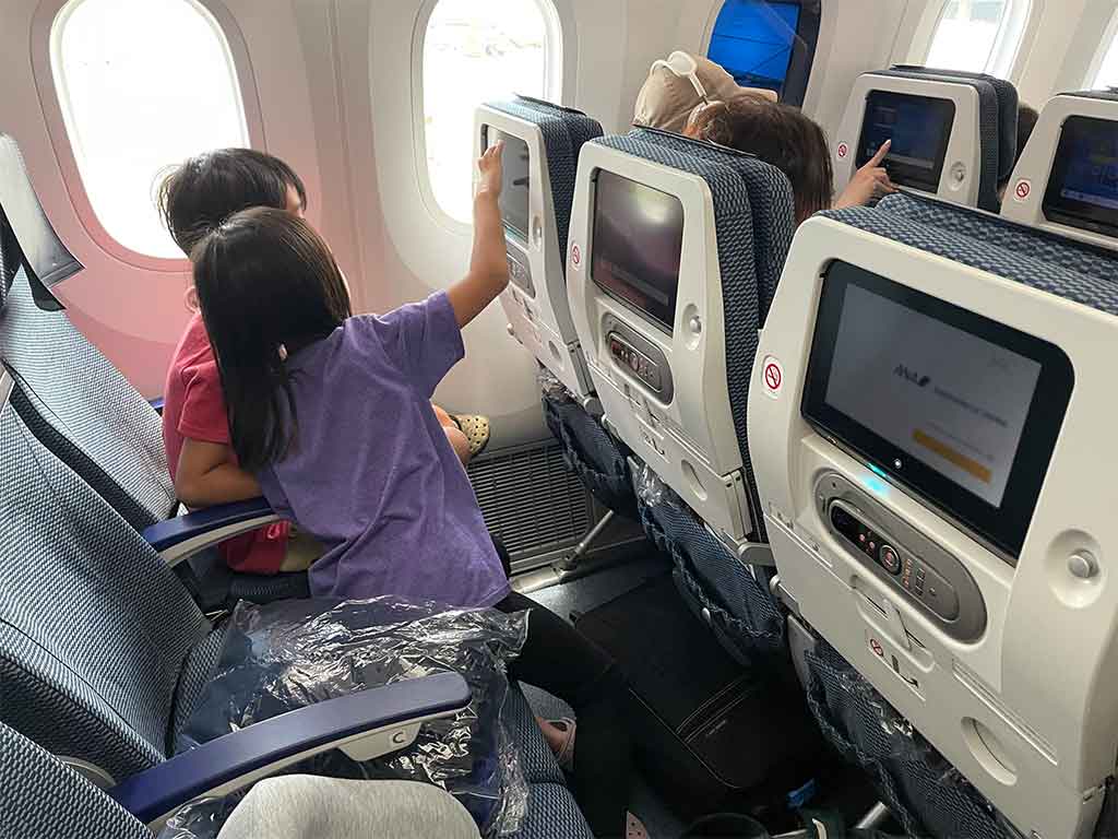 日系航空会社は日本語の番組が多く、子どもたちは夢中になって楽しんでいた【写真:i-know】