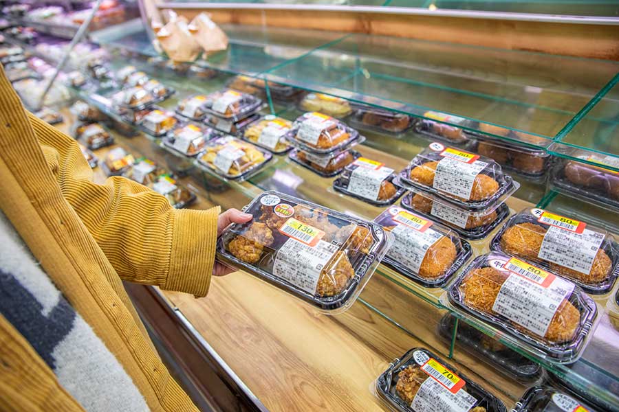 値引きされた惣菜を手に取る利用客(写真はイメージ)【写真:PIXTA】