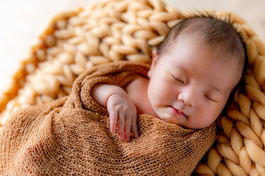 おくるみに包まれて眠る赤ちゃん（写真はイメージ）【写真：PIXTA】
